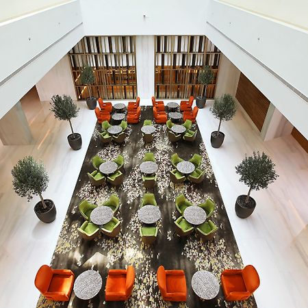 迪拜大都会大酒店 外观 照片 The photo showcases a modern interior space, likely a hotel or a lounge. The setting features a large, open area with a stylish arrangement of seating. 

There are vibrant orange and green chairs arranged around circular tables, providing a cozy atmo
