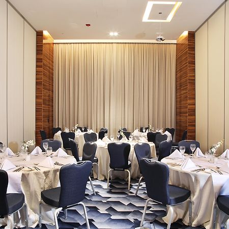 迪拜大都会大酒店 外观 照片 The photo shows an elegantly arranged dining area with several round tables. Each table is covered with white tablecloths and set with folded napkins, glassware, and cutlery, indicating that it is prepared for a formal event. The chairs surrounding t
