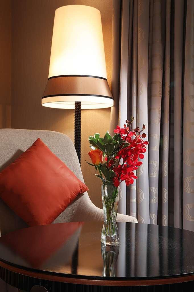迪拜大都会大酒店 客房 照片 The photo shows a cozy corner with a modern armchair that has a light gray fabric. It features a bright orange decorative pillow on one side. Next to the chair is a stylish lamp with a wide shade that emits a warm light. On a small table beside the c