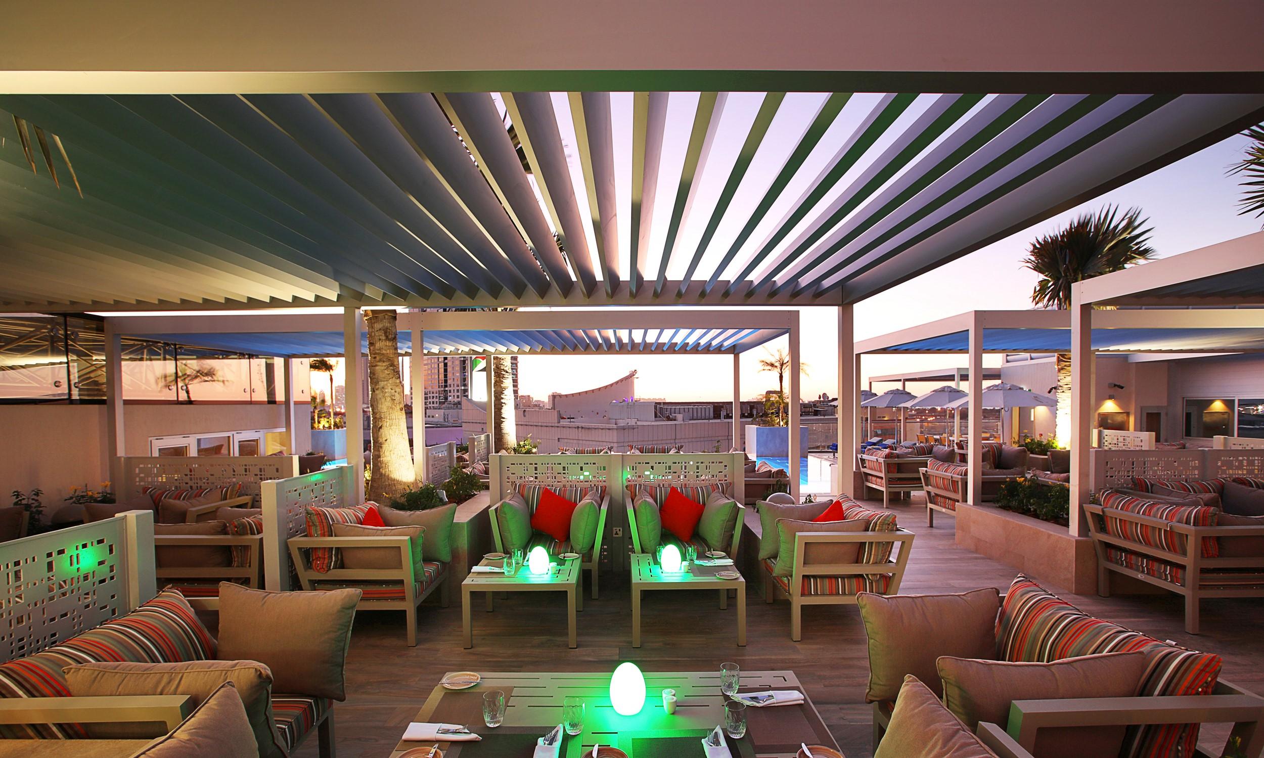 迪拜大都会大酒店 外观 照片 The photo depicts a stylish outdoor lounge area, likely located on a rooftop or terrace. The space features modern furnishings with comfortable seating, including sofas and tables. There are colorful cushions accenting the seating, and some tables ha