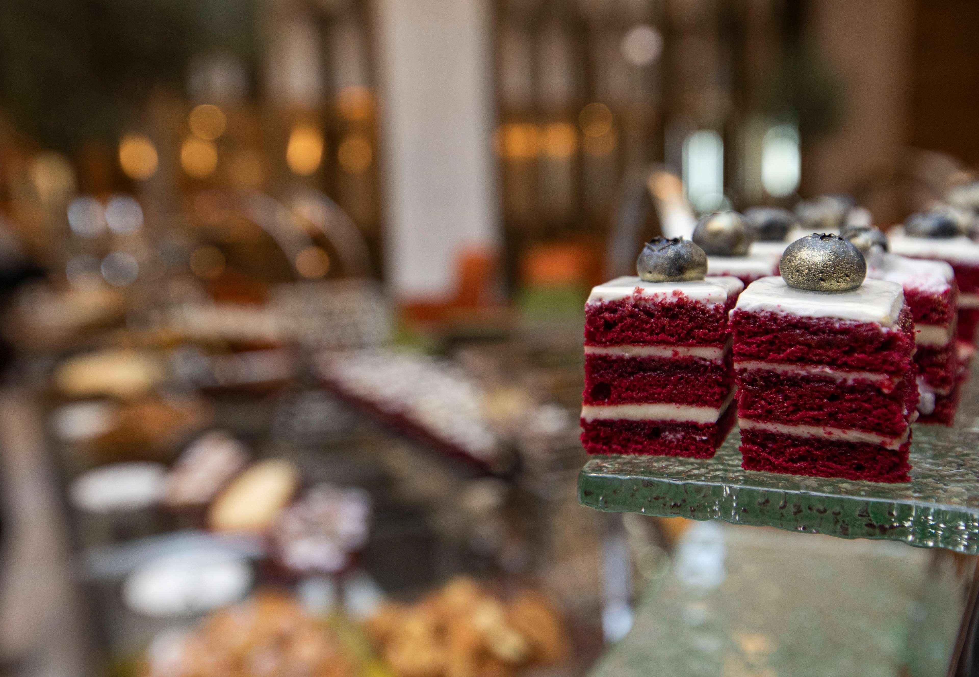 迪拜大都会大酒店 外观 照片 The photo showcases a selection of desserts, with a particular focus on red velvet cake squares. The cake pieces are layered, featuring a rich red color and topped with a small decoration. In the background, there are various other desserts and pastr