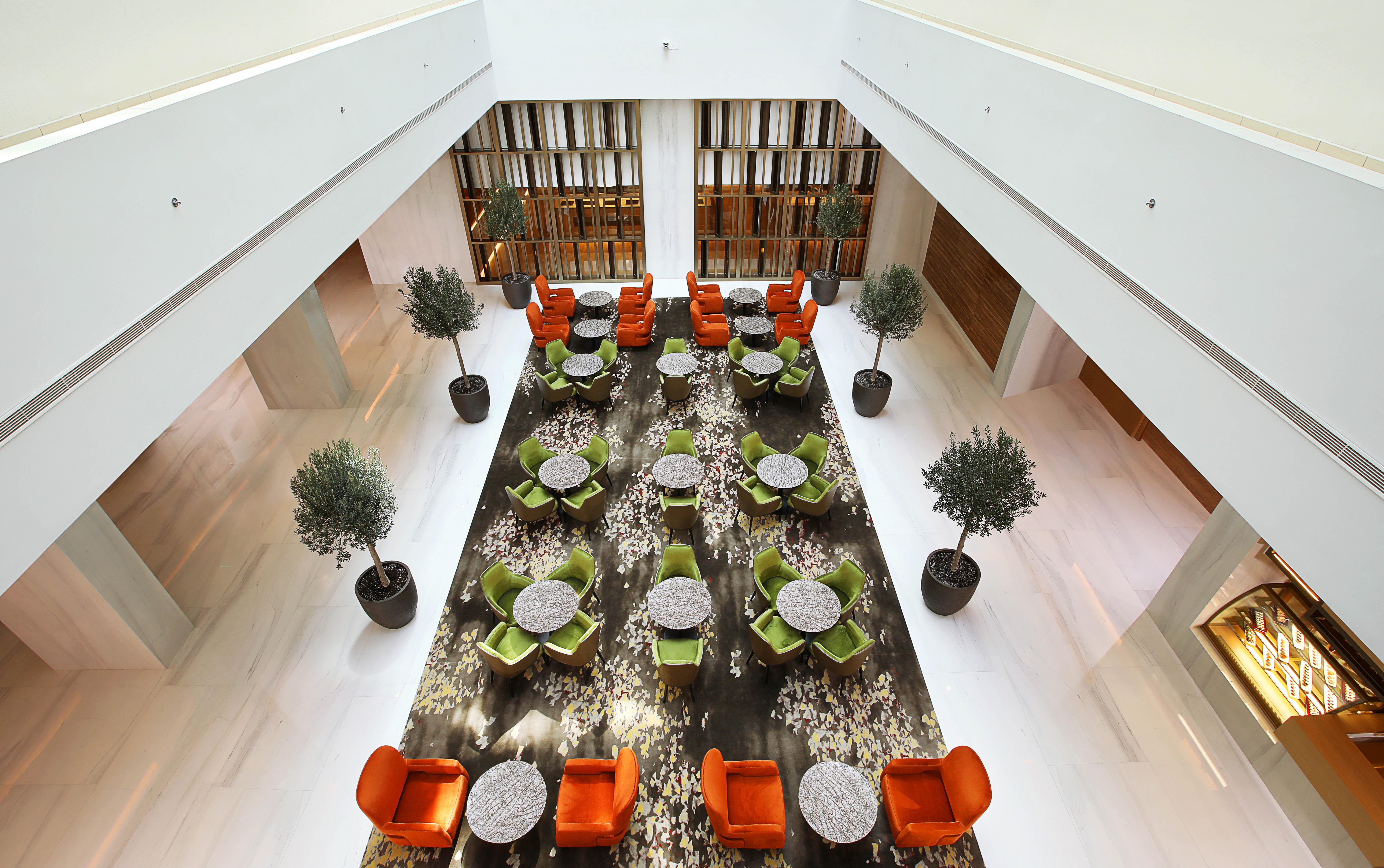迪拜大都会大酒店 外观 照片 The photo showcases a modern interior space, likely a hotel or a lounge. The setting features a large, open area with a stylish arrangement of seating. 

There are vibrant orange and green chairs arranged around circular tables, providing a cozy atmo