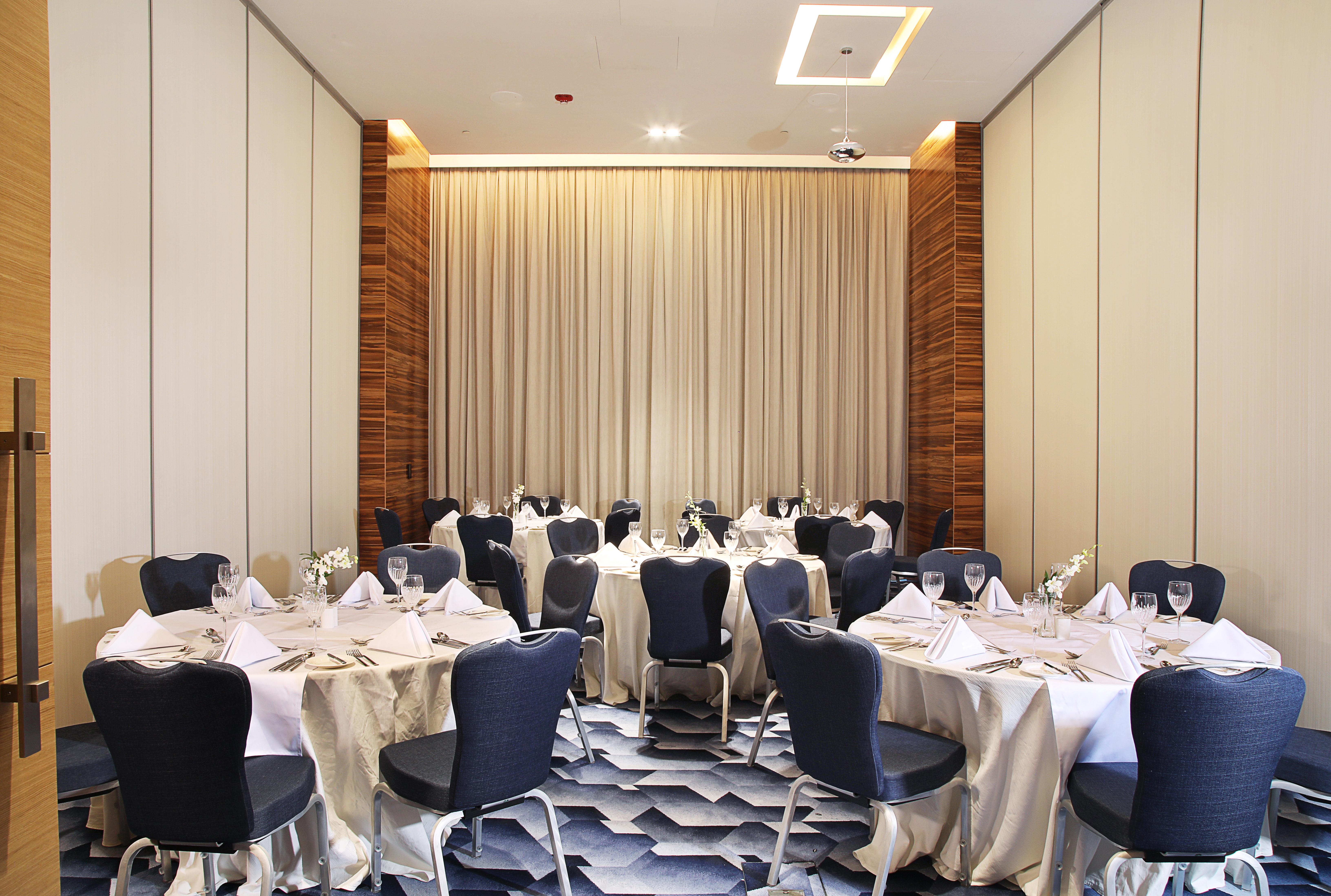 迪拜大都会大酒店 外观 照片 The photo shows an elegantly arranged dining area with several round tables. Each table is covered with white tablecloths and set with folded napkins, glassware, and cutlery, indicating that it is prepared for a formal event. The chairs surrounding t