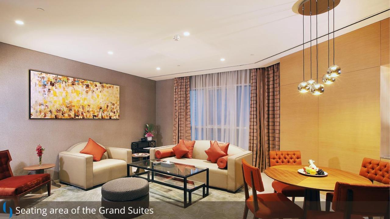迪拜大都会大酒店 外观 照片 The photo depicts a stylish and modern living area within a suite. There is a light-colored sofa with decorative cushions, a glass coffee table in the center, and a cozy armchair nearby. To the side, there is a small round dining table with four chai