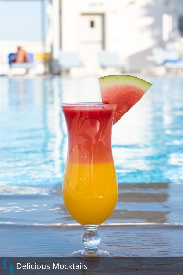 迪拜大都会大酒店 外观 照片 The image features a colorful drink in a tall glass. The beverage has a gradient effect, with vibrant red at the top gradually transitioning to a bright yellow at the bottom. A slice of watermelon is perched on the rim of the glass, adding a decorati