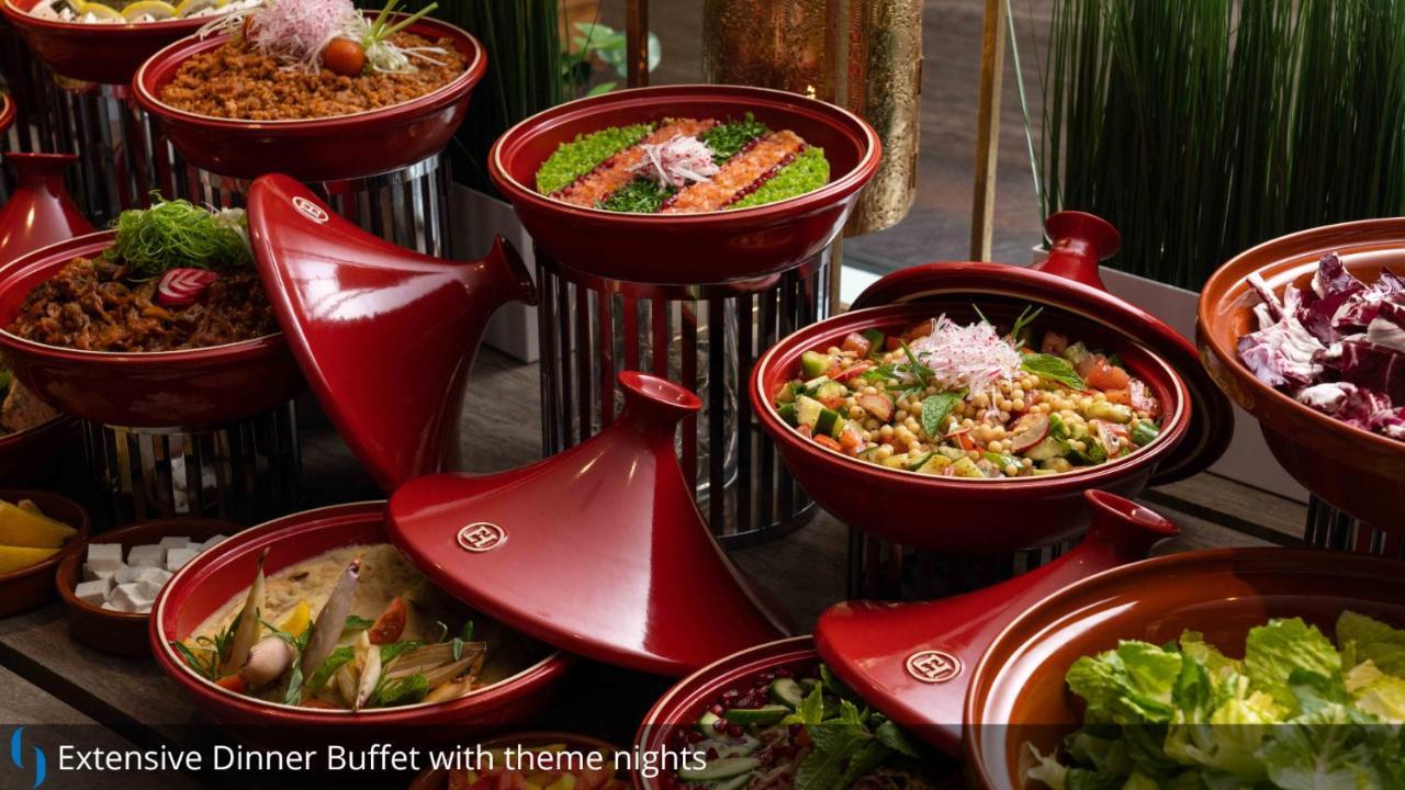 迪拜大都会大酒店 外观 照片 The photo displays an assortment of colorful dishes arranged in red ceramic containers. Each dish appears to have various ingredients, likely featuring a mix of vegetables, proteins, and grains. The presentation is visually appealing, with vibrant gr