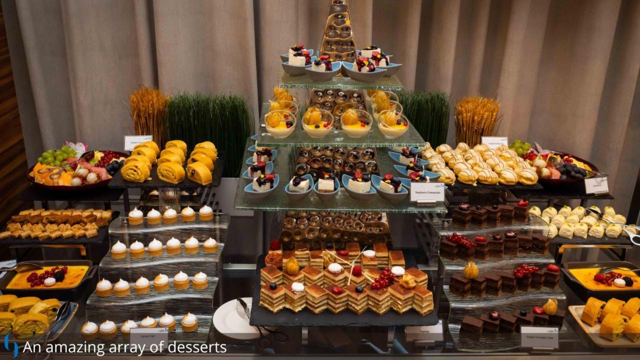 迪拜大都会大酒店 外观 照片 The photo showcases an impressive assortment of desserts arranged elegantly. There are multiple tiers of sweets, including small pastries, cakes, and colorful treats. The display features a variety of chocolate-covered items, fruit-topped desserts, a