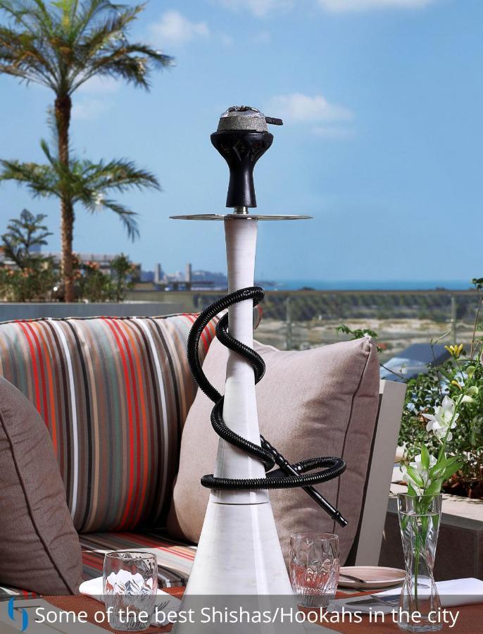迪拜大都会大酒店 外观 照片 The photo features a hookah, also known as a water pipe, placed on a table. The hookah has a tall, slender body with a bowl at the top for placing tobacco. A flexible hose is coiled around the base of the hookah, which is connected to the main body. 