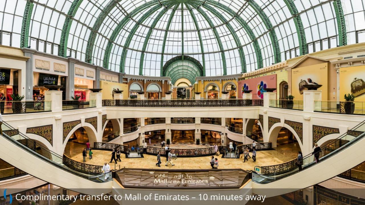 迪拜大都会大酒店 外观 照片 The photo shows the interior of a large shopping mall, featuring an expansive, open layout with multiple levels. There is a stunning glass dome ceiling that allows natural light to illuminate the space, highlighting the luxurious architecture. The ar