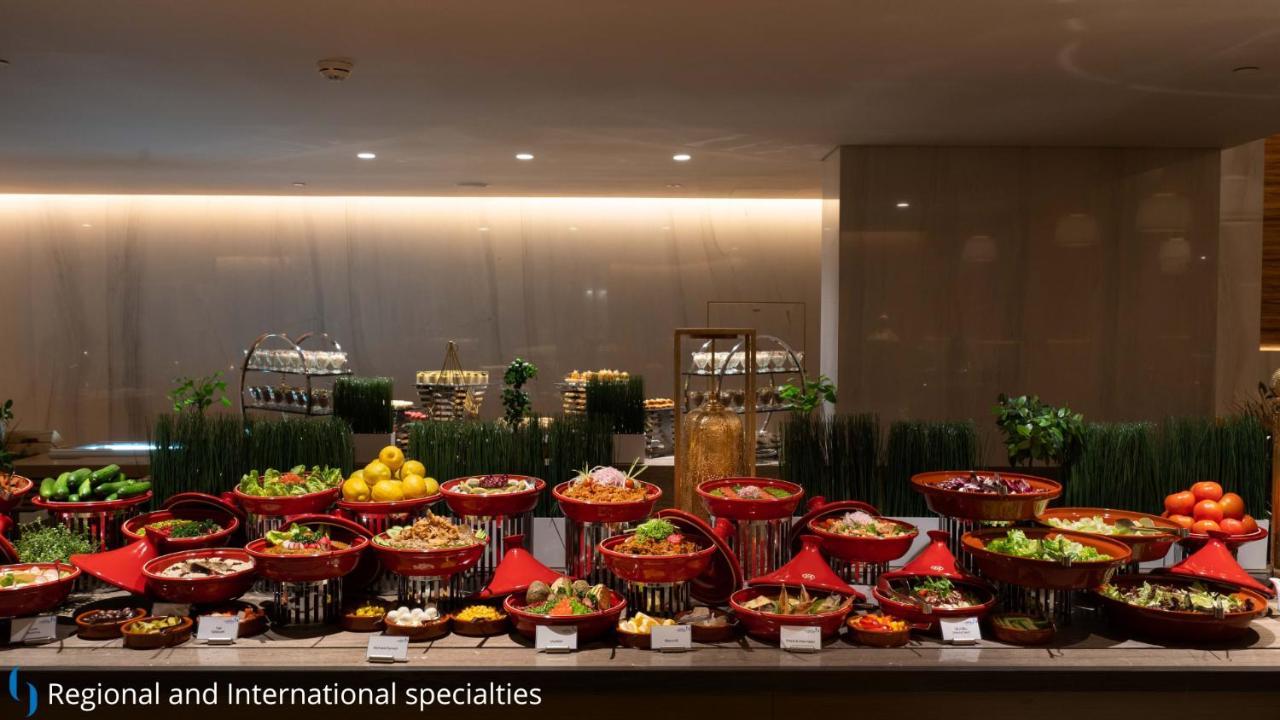 迪拜大都会大酒店 外观 照片 The photo displays a buffet setup featuring a variety of dishes arranged in decorative baskets. There are multiple red baskets filled with a range of colorful dishes, including salads, fruits, and other culinary specialties. The background has a mode