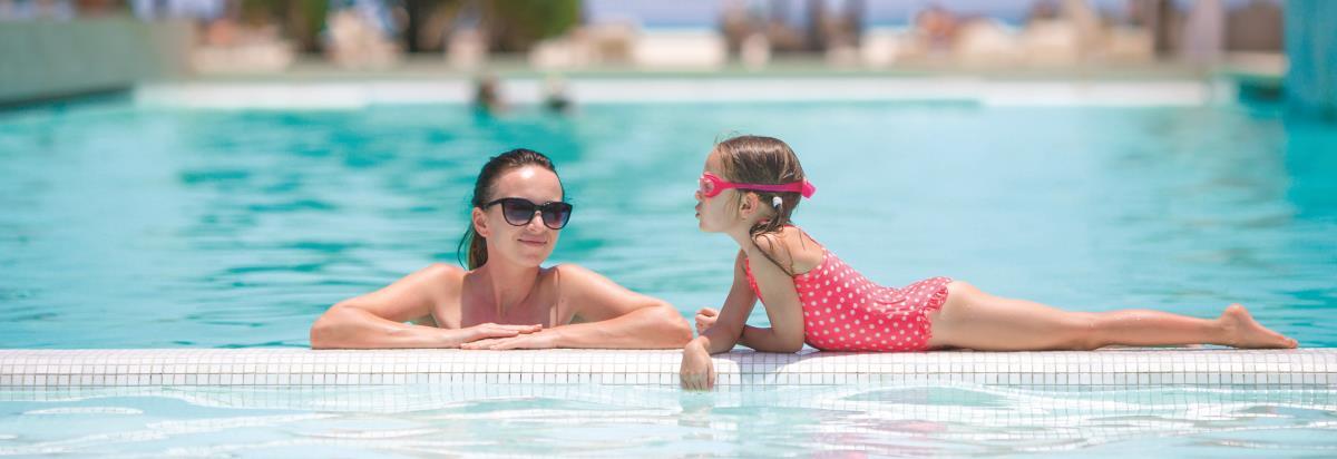 迪拜大都会大酒店 外观 照片 The photo shows a woman and a girl in a swimming pool. The woman is wearing sunglasses and appears relaxed, leaning on the edge of the pool. The girl, wearing a pink swimsuit with white polka dots and swim goggles, is playfully leaning over the edge 